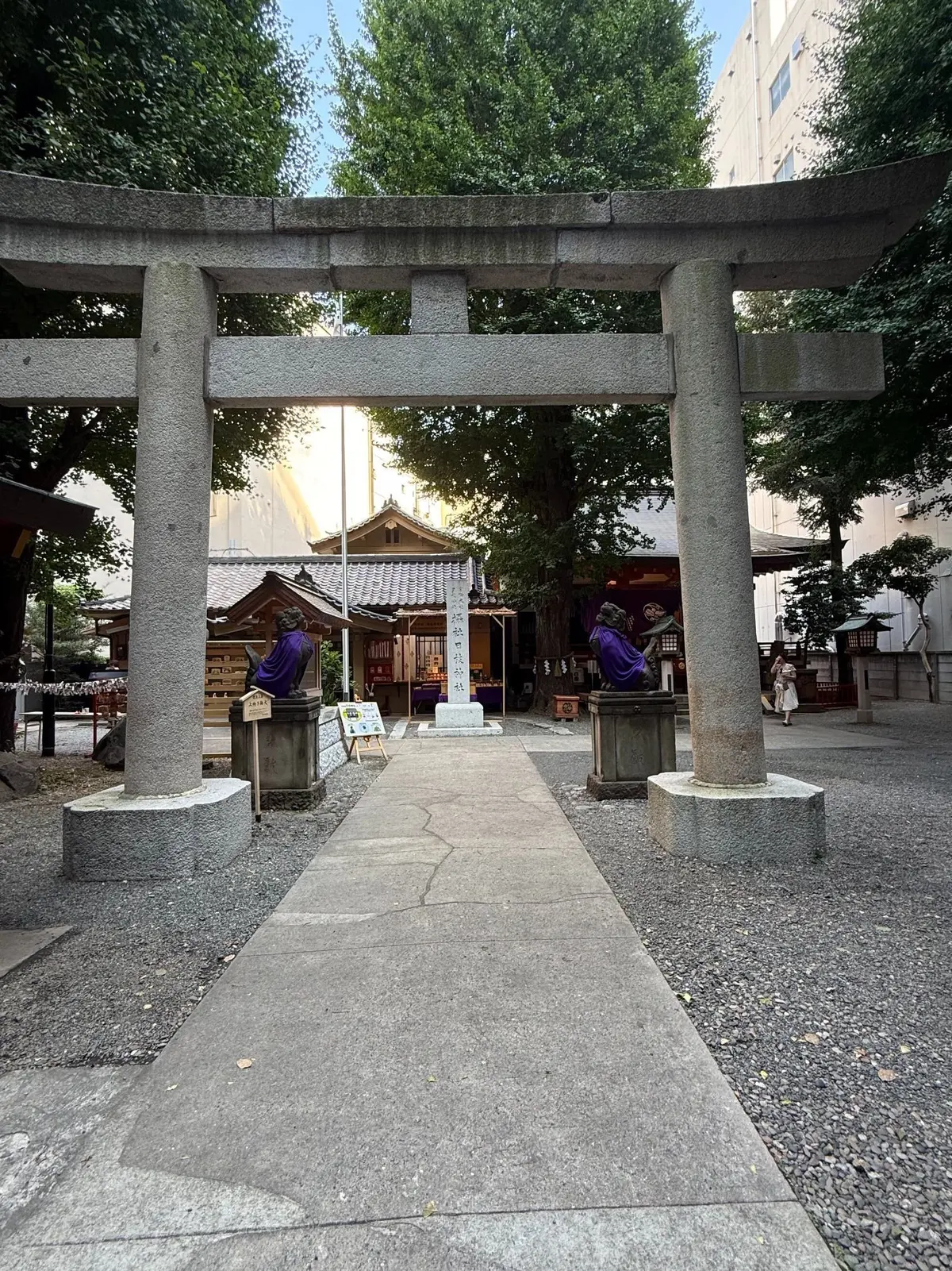 鳥居が並ぶ参道。中央には石碑があり、左右に獅子頭の置物が置かれている。背景には朱色の社殿が見える。
