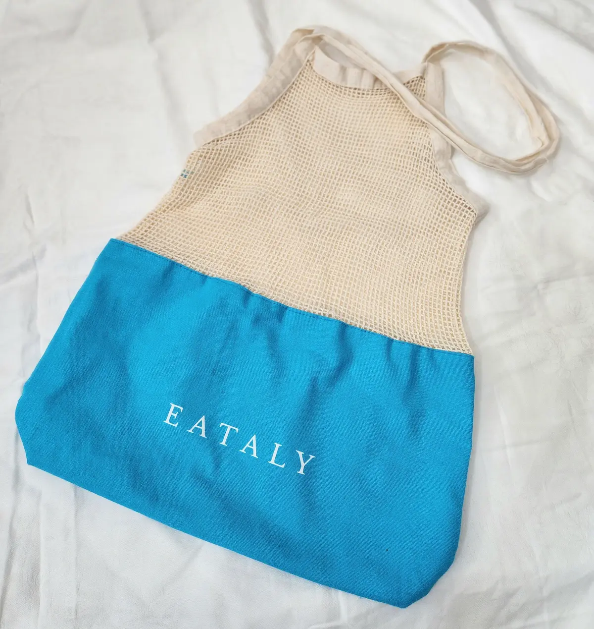 ベージュと青の2色使いのメッシュトートバッグで、青い部分に「EATALY」の文字が書かれている