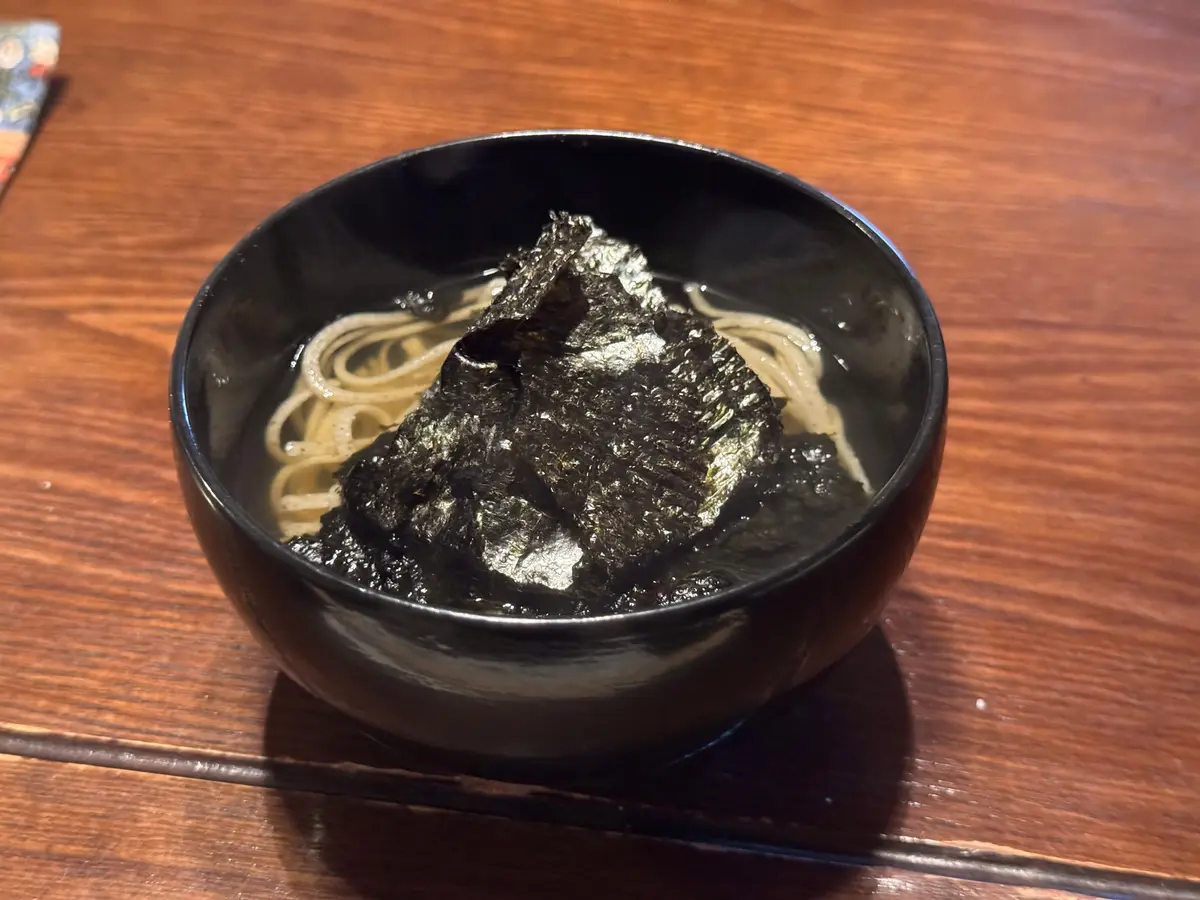 黒いボウルに、細い麺と濃い海藻が盛り付けてある。
