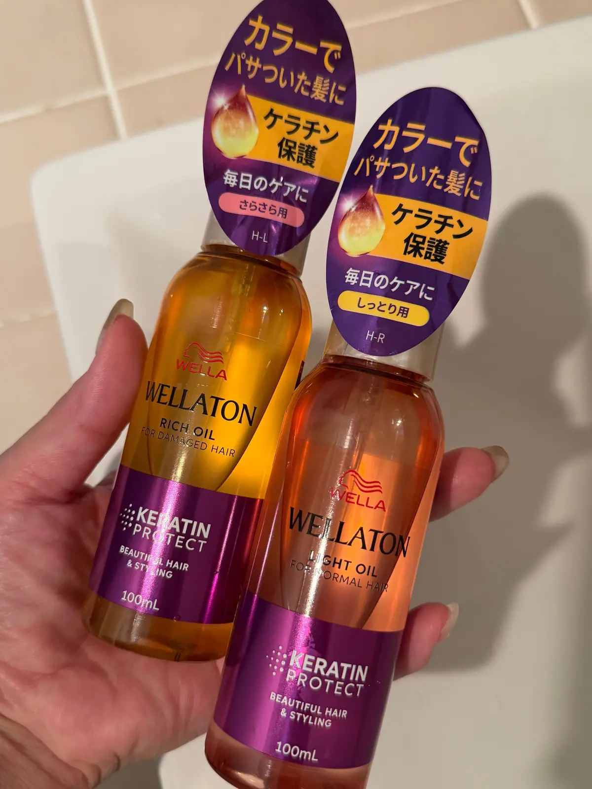 ウェラトン（Wellaton）のヘアオイル2本。左はオレンジ色のボトルで「ダメージヘア用」、右はピンク色のボトルで「ノーマルヘア用」。それぞれ100ml。製品のパッケージにはケラチン保護の記載がある。