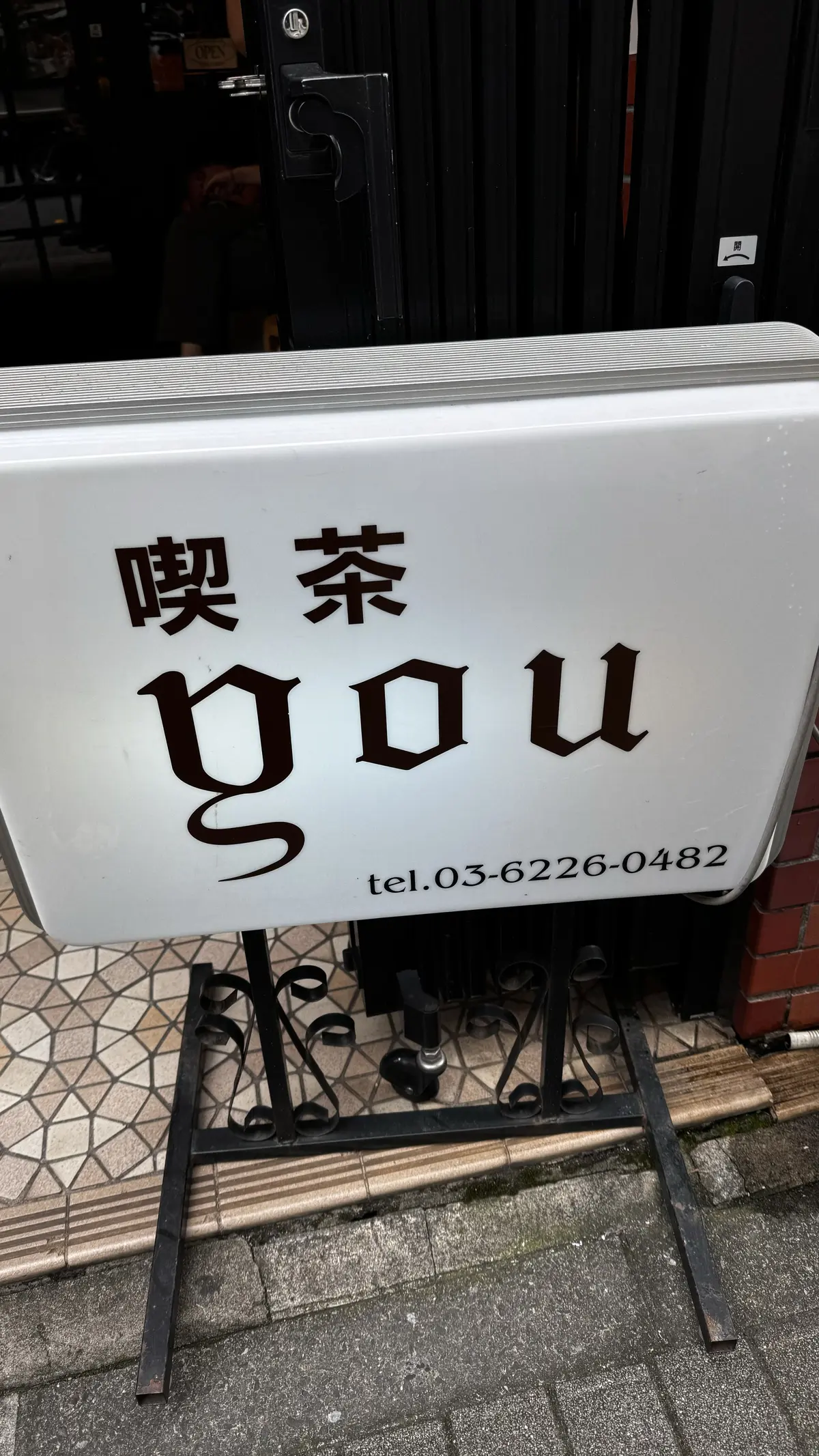 喫茶の看板が白地に黒文字で「喫茶 YOU」と書かれ、電話番号も表示されている