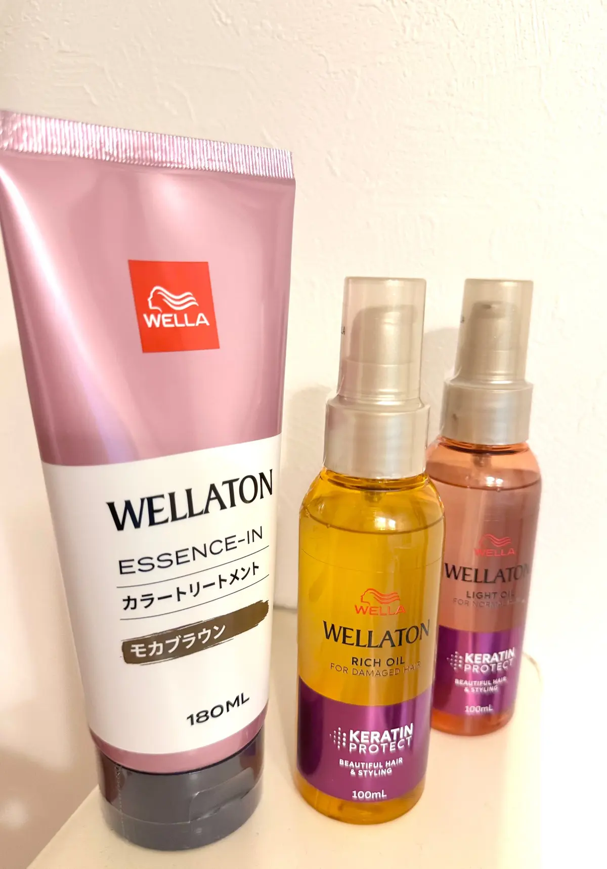 左から、ウェラ（WELLA）のピンク色のチューブ容器に入った「エッセンスイン カートリートメント」、真ん中がオレンジ色のボトルに入った「リッチオイル」、右側が茶色のボトルに入った「ライトオイル」。いずれもウェラ（WELLA）のヘアケア製品。