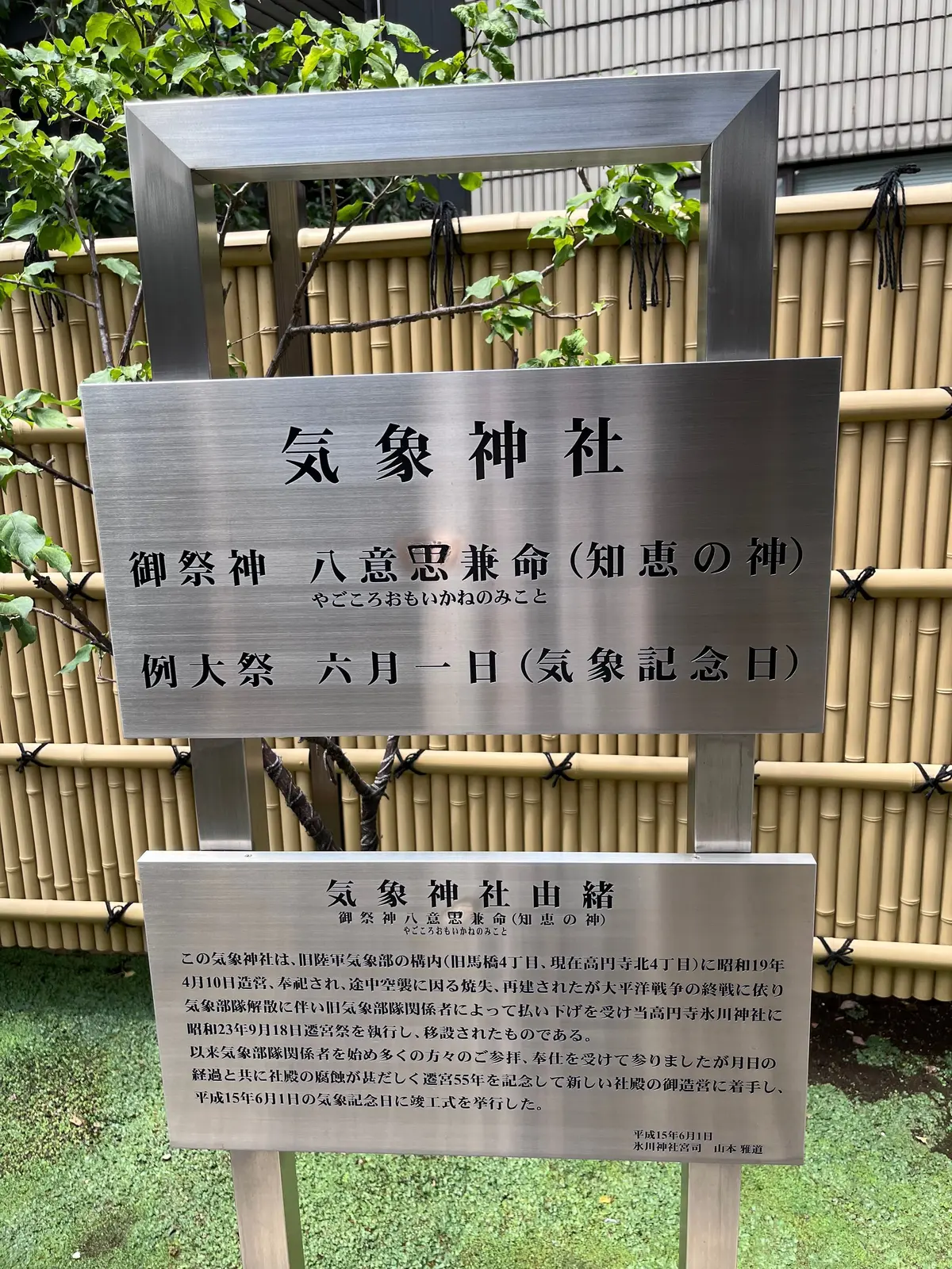木製の鳥居と社殿が見える鳥居の前に設置された石碑。碑文には「気象神社」「八意思兼命（知恵の神）」などの文字が刻まれている。下部には神社の由緒書きが記載されている。