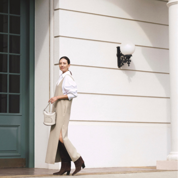 スリットからロングブーツをのぞかせる旬なバランスで白×ベージュの上品配色をモードに仕上げる。気温19℃｜11/3(月)【50代の毎日コーデ】