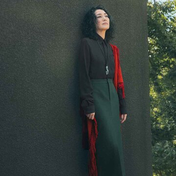 「トッズ」のダークブラウンシャツでつくるモダンスタイル。秋の差し色にふさわしい赤のストールが華を添える